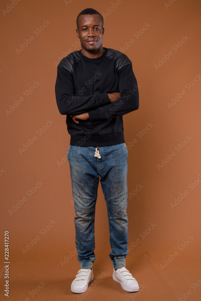 Studio shot of young African man against brown background Studio shot of young African man against brown background