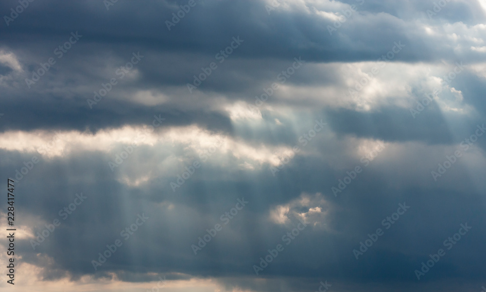 Dramatic dark and light cloudy sky with rays of sunlight