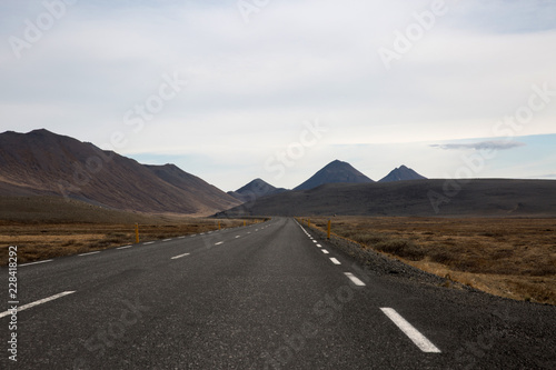 Long Empty Road in Iceland with Mountains and Hills in background