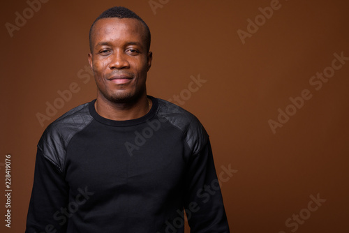 Studio shot of young African man against brown background © Ranta Images