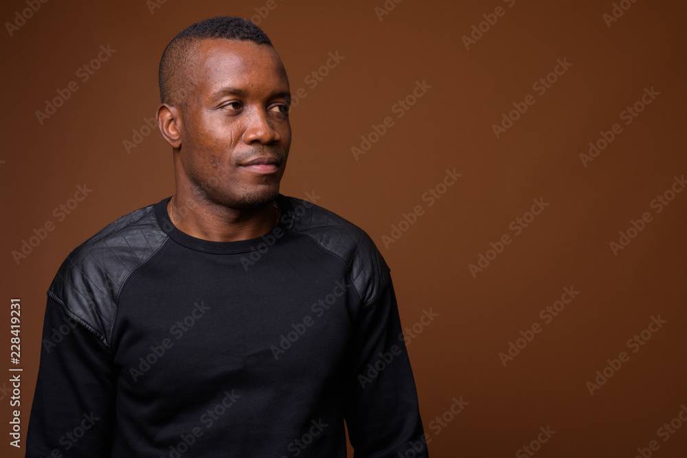 Studio shot of young African man against brown background Studio shot of young African man against brown background