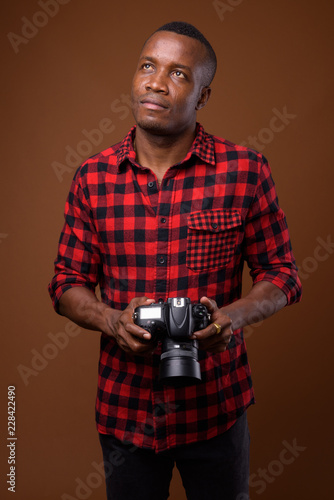 Studio shot of young African man against brown background