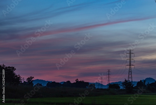The light of sunset behind the mountain and the high voltage poles.