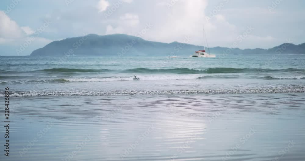 Background of sailboat and low tide waves rolling onto tropical beach Background of sailboat and low tide waves rolling onto tropical beach