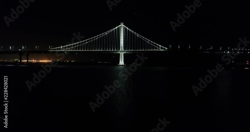 Aerial shot of vehicles moving on San Francisco‚ÄìOakland Bay Bridge with city in background at Night