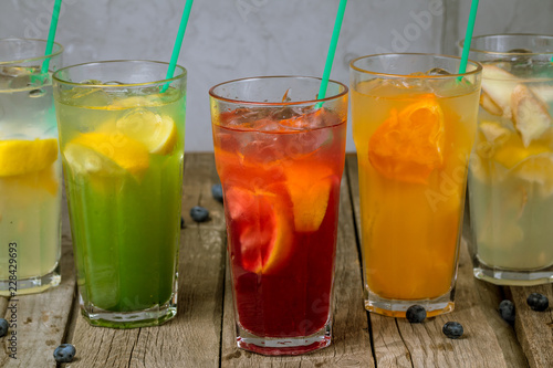 different lemonades in glasses on wooden background