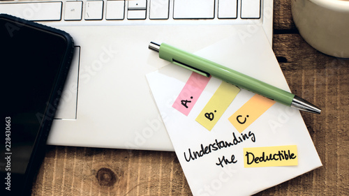 Insurance terms and insurance policy concept ABC's of insurance understanding the deductible notebook and pen on table