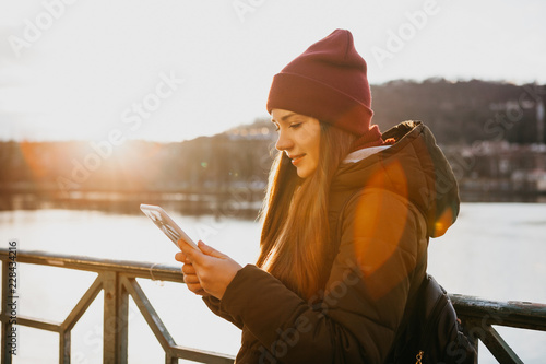 A tourist girl on the street in Prague at sunset uses a tablet in order to view the map or the Internet or use a mobile application. photo