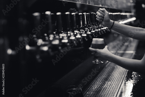 black and white row of beer taps with arms and full glass