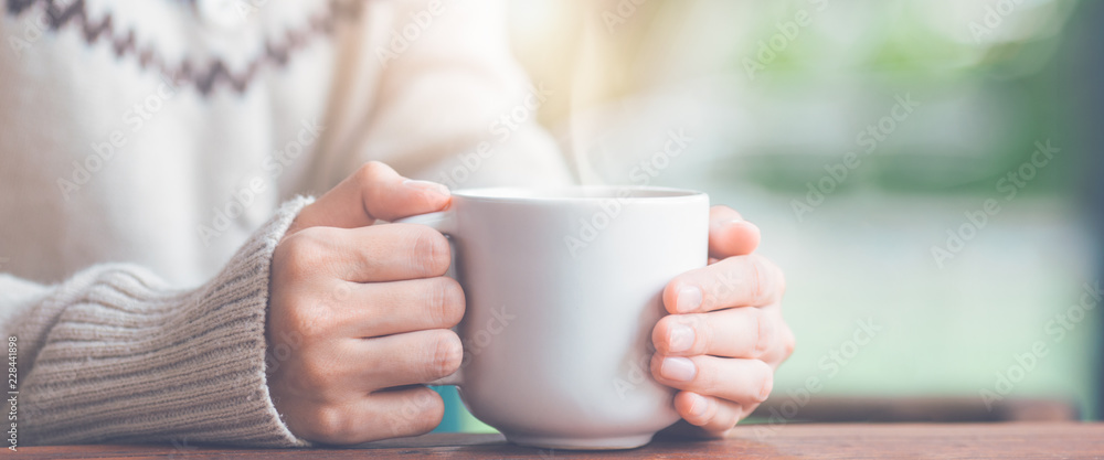 Woman hand in warm sweater holding a cup of coffee.Web banner. Woman hand in warm sweater holding a cup of coffee.Web banner.