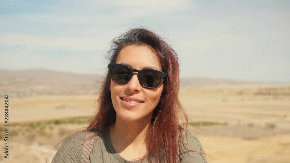 Young Attractive Smiling Mixed Raced Girl Portrait in a Desert. Happy Tourist Woman Posing on Camera with Hair Waving in the Wind. Cappadocia, Turkey. 4K Slowmotion. Young Attractive Smiling Mixed Raced Girl Portrait in a Desert. Happy Tourist Woman Posing on Camera with Hair Waving in the Wind. Cappadocia, Turkey. 4K Slowmotion.