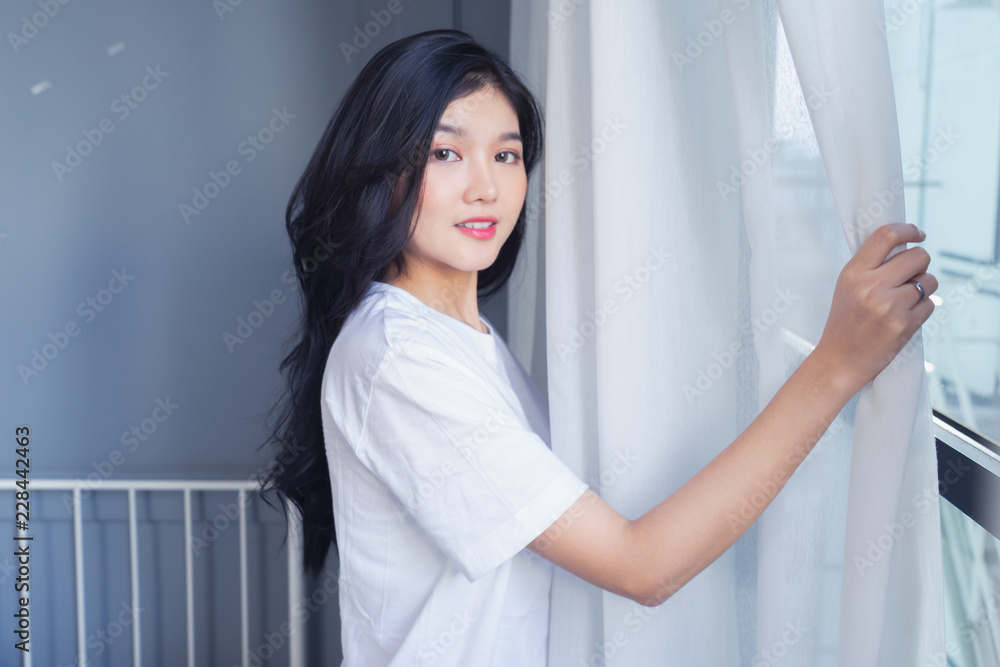 Woman stretching in bed after waking up, back view. Woman sitting near the big white window while stretching .she happy and smile. Woman stretching in bed after waking up, back view. Woman sitting near the big white window while stretching .she happy and smile.