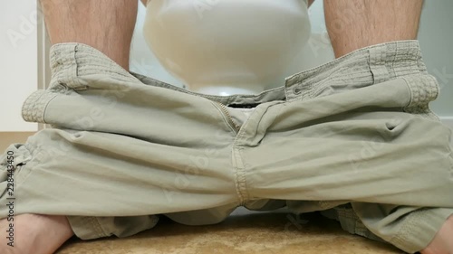 A dolly shot of a man using the restroom