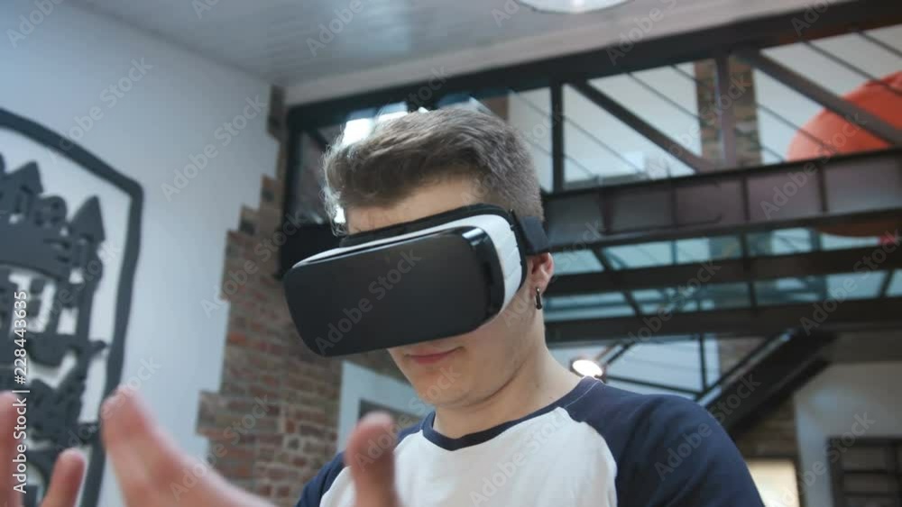 Portrait of cute Caucasian guy wearing virtual reality headset. Nice young Slavic man viewing hands, looking around. Amazing modern design of flat. Portrait of cute Caucasian guy wearing virtual reality headset. Nice young Slavic man viewing hands, looking around. Amazing modern design of flat.