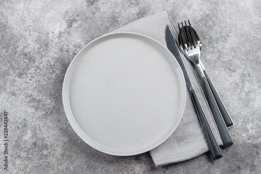 Empty ceramic grey plate and cutlery, knife, fork, spoon on gray stone concrete table background. Copy space. Menu Recipe Concept - obrazy, fototapety, plakaty 