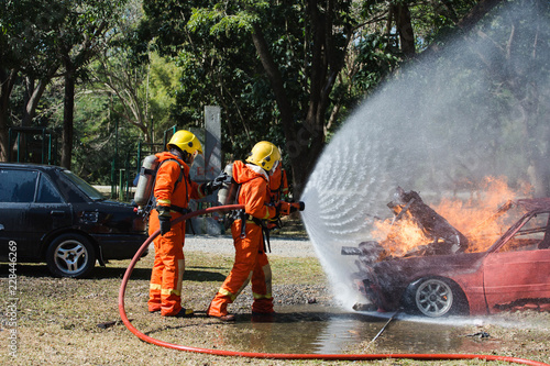 two firefighters water spray by high pressure nozzle in fire fighting operation / Fire and rescue training school regularly to get ready. 