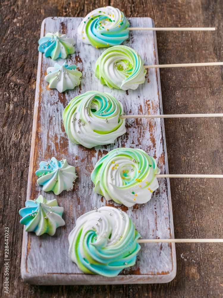 Colored meringues on a wooden background. Traditional French sweets. Vertical shot
