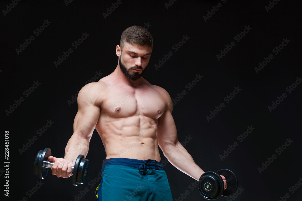 Muscular bodybuilder guy doing exercises with dumbbell over black background Muscular bodybuilder guy doing exercises with dumbbell over black background