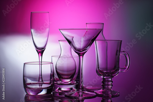 Glass, transparent, different glassware stand on a bright background with rays of white light.