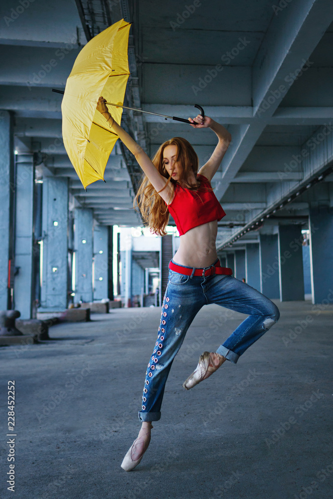 Ballerina is dancing with a yellow umbrella in jeans, T-shirt and pointe.  Street performance. Modern ballet. Slender girl dancing on tiptoe. Red hair  fly. Stock Photo | Adobe Stock