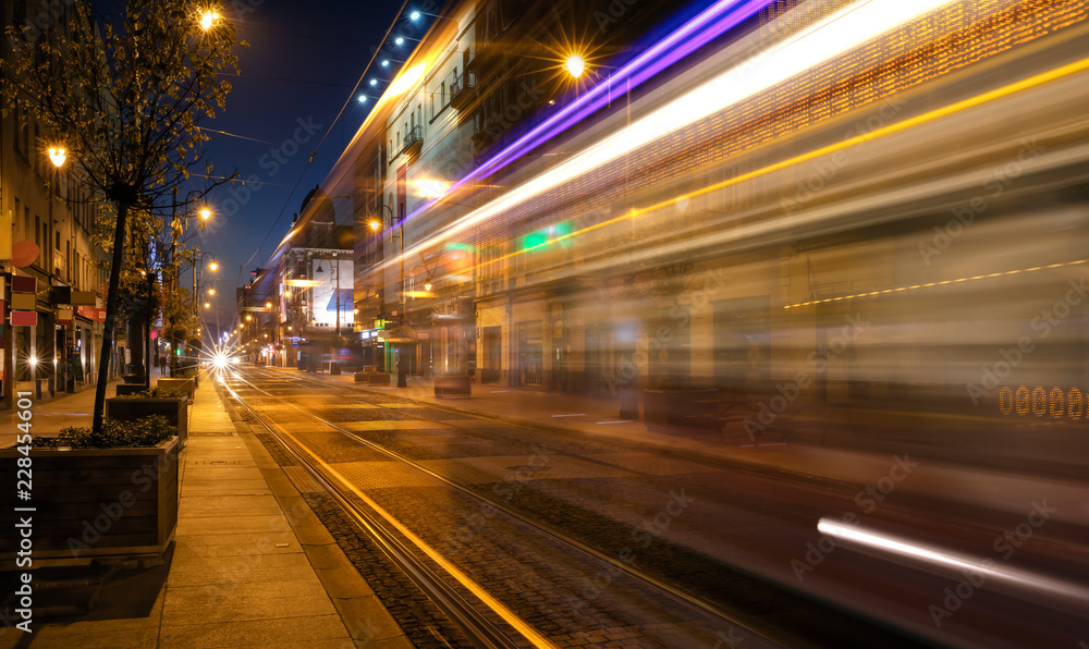 Light trails of a tram driving a street by night