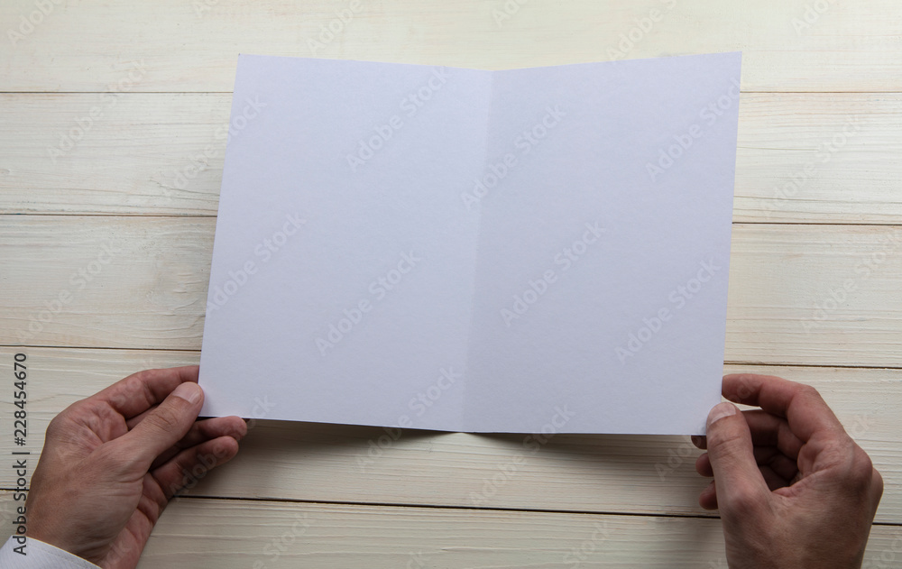 Mens hands holding empty white booklet Mens hands holding empty white booklet