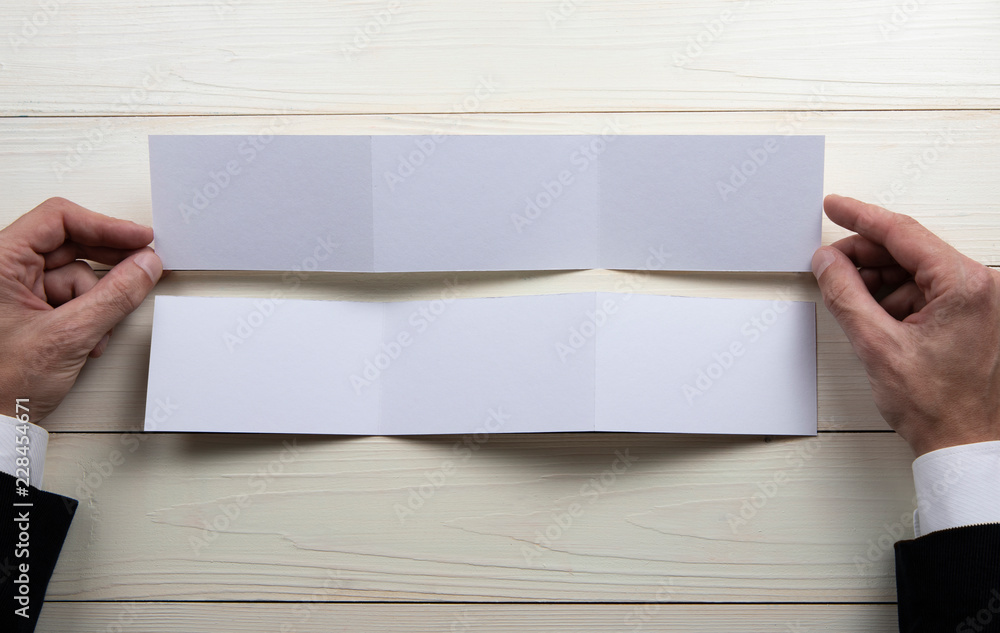 Mens hands holding empty white booklet Mens hands holding empty white booklet