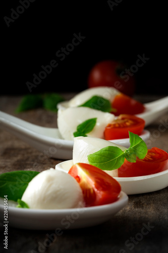Spoons with mozzarella cheese balls, cherry tomato and basil