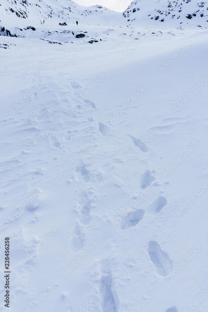 following a shoe in deep snow after a snowfall during a transition through the mountains and rocks