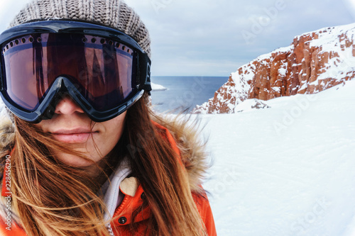 a girl in warm protective gear and a large glass mask on her face during a winter hike to the rocks in
