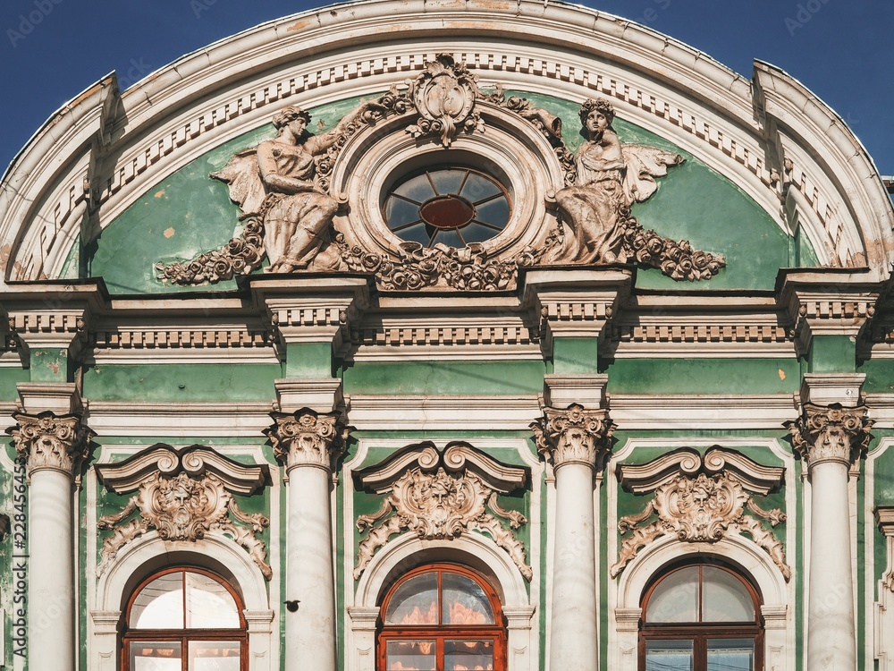 Facade of green historical building with figures, columns in St. Petersburg