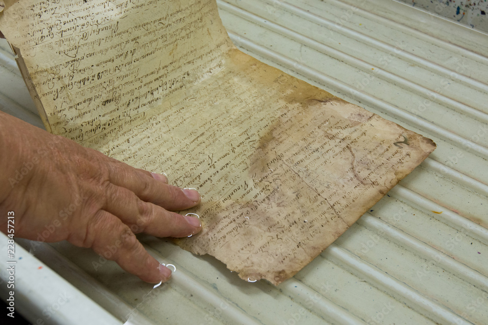 Naklejka premium Restoration laboratory. Washing of a sheet of an old book, conservation