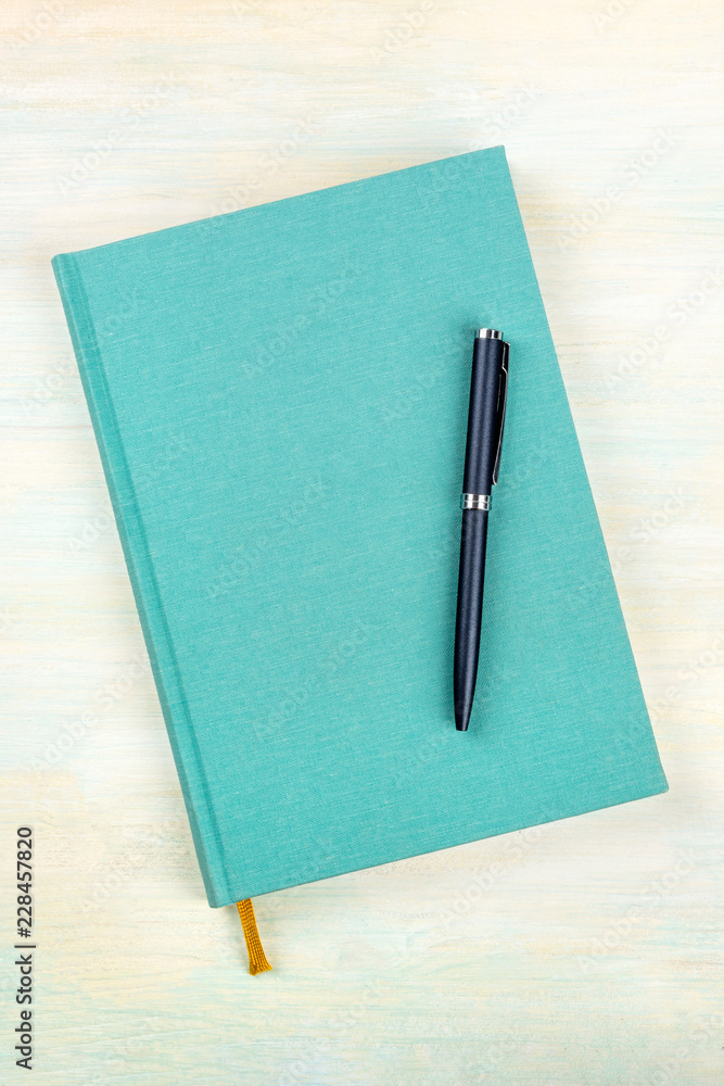 An overhead photo of a teal blue journal with a pen, an elegant notebook or planner with a place for text An overhead photo of a teal blue journal with a pen, an elegant notebook or planner with a place for text