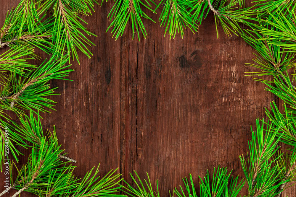 A Christmas composition with fir tree branches on a dark wooden background with copy space, shot from the top A Christmas composition with fir tree branches on a dark wooden background with copy space, shot from the top