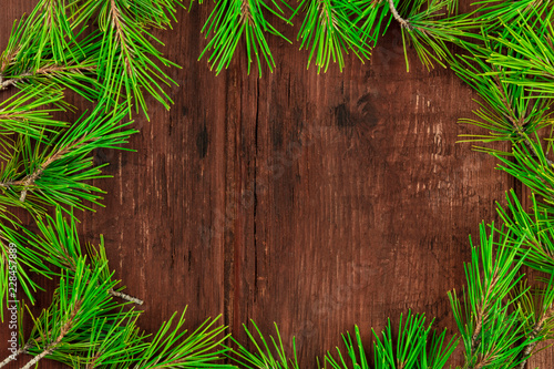 A Christmas composition with fir tree branches on a dark wooden background with copy space, shot from the top