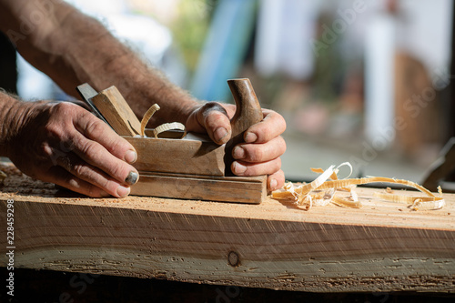Handwerkerhände mit altem Holzhobel beim abhobeln eines Hozbalken