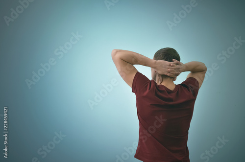 Obraz na plátně Thinking man is standing and is relaxing and is looking ahead by holding his hands behind his head