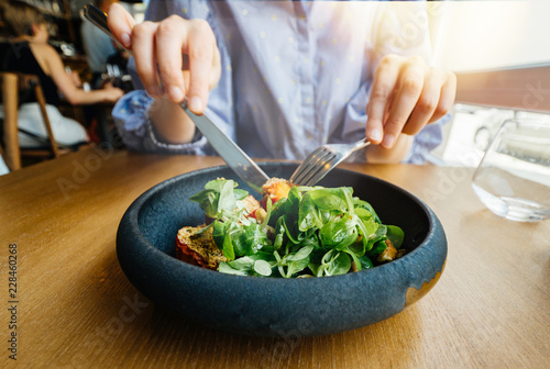 Front view of french woman eating delicious green gourmand organic salad in Restaurant using fork and knife