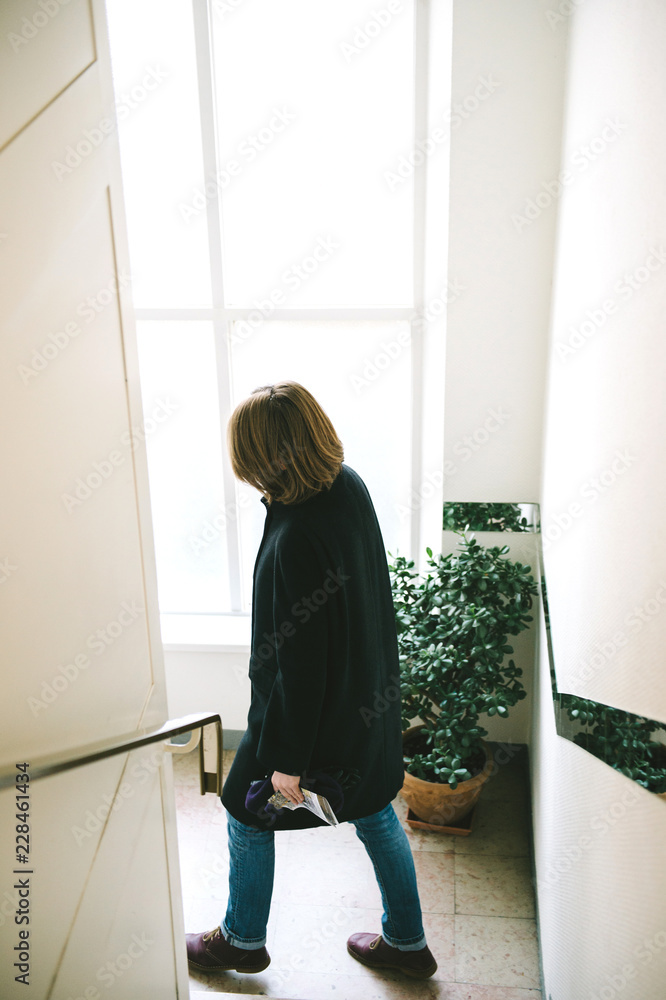 Woman descending stairs in bright corridor Woman descending stairs in bright corridor