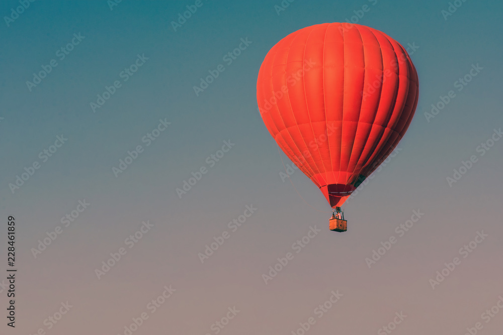 Obraz premium Red balloon in the sky. Aerostat. People in the basket. Fun. Summer entertainment. Romantic adventures. Modern toned photo.
