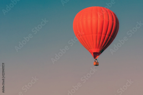 Red balloon in the sky. Aerostat. People in the basket. Fun. Summer entertainment. Romantic adventures. Modern toned photo.