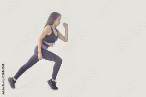 Side view full length portrait of a young fitness woman running isolated over gray background