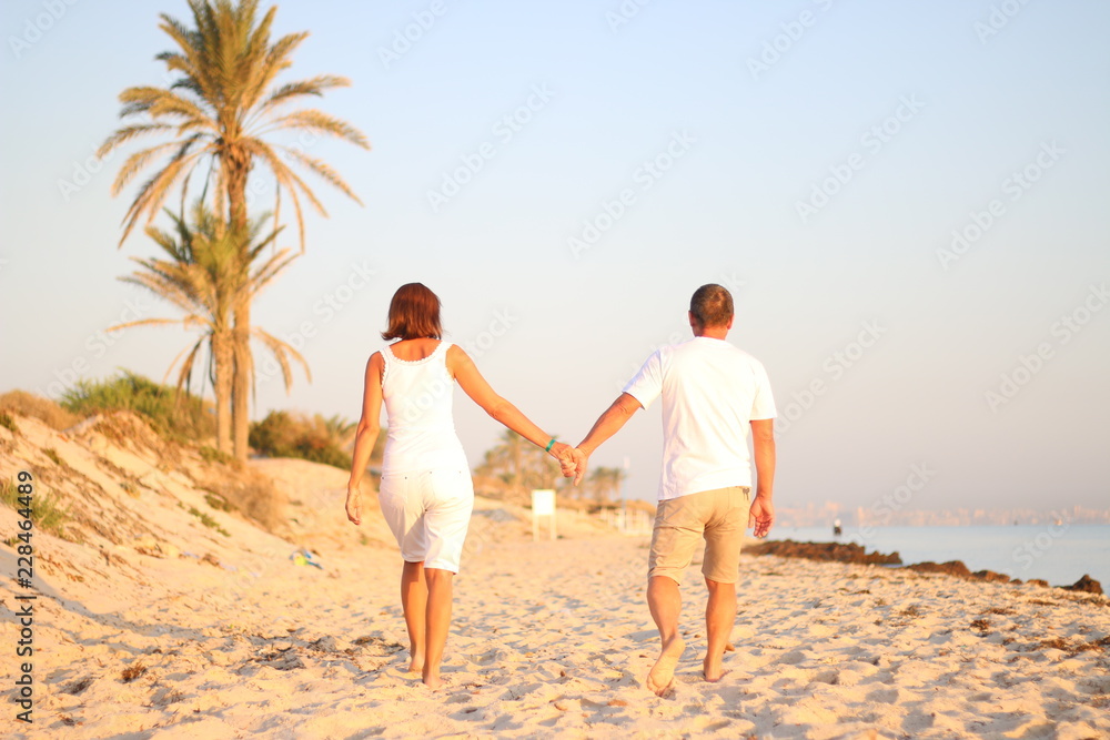 adult couple go by the hand on beach adult couple go by the hand on beach