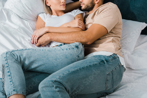 cropped image of young couple hugging on bed in bedroom