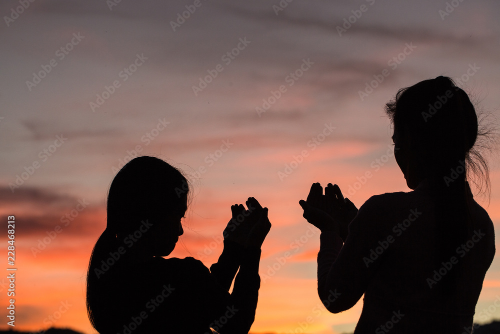 Silhouette of two women praying to god with the bible. Woman Pray for god blessing to wishing have a better life. Christian life crisis prayer to god.