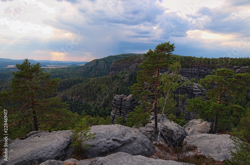 Scenic panorama with typical rocky peaks, ancient forest under cloudy sky. Bohemian Switzerland National Park. Famous touristic place and travel destination in Europe. Czech Republic