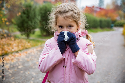 Fotografie Sick little girl with cold and flu standing outdoors