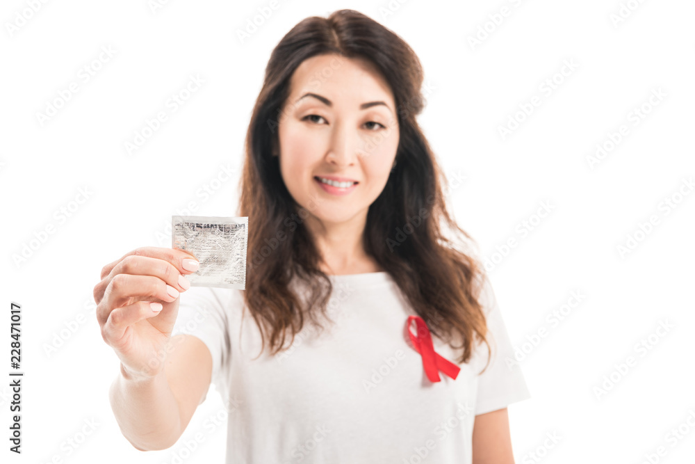 smiling adult asian woman with aids awareness red ribbon on t-shirt holding condom isolated on white smiling adult asian woman with aids awareness red ribbon on t-shirt holding condom isolated on white