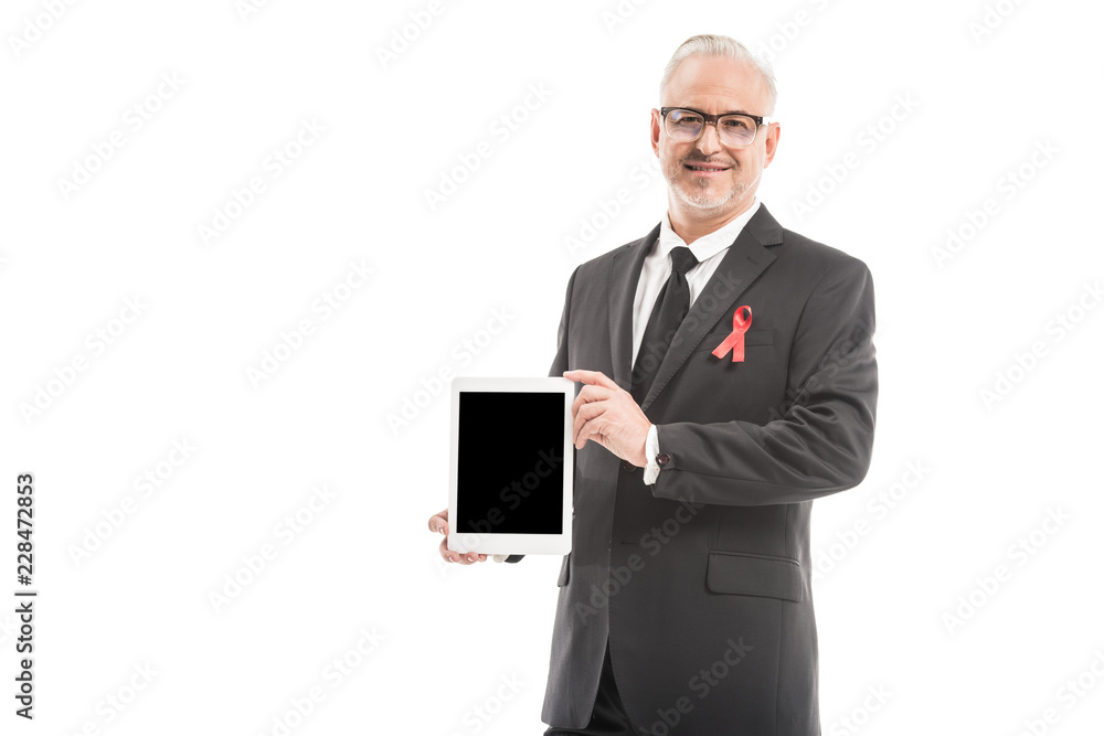 mature businessman in suit with aids awareness red ribbon holding tablet with blank screen isolated on white mature businessman in suit with aids awareness red ribbon holding tablet with blank screen isolated on white