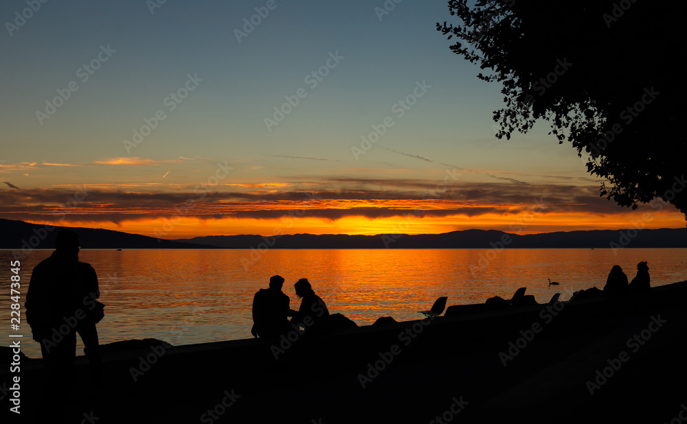 Obraz premium Sunset. People. Silhouette. Lake. Sky. Evening